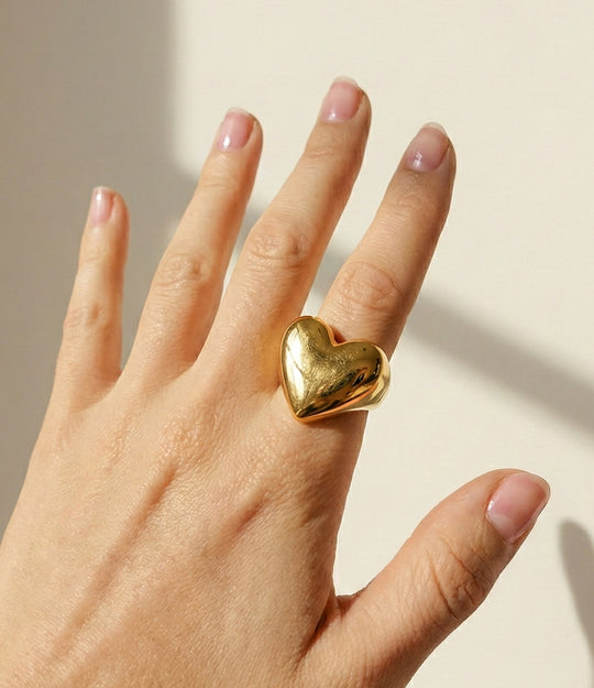 Model wearing the True Love Ring in 18k gold plated finish, featuring a sleek heart-shaped statement design made of waterproof stainless steel, isolated on white.