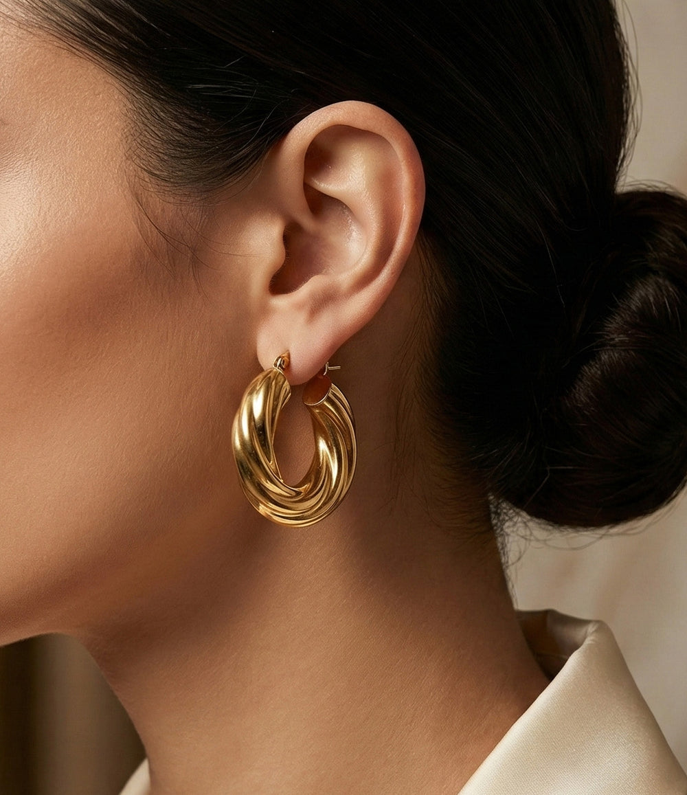 Close-up of a person wearing a gold hoop earring with a blurred background