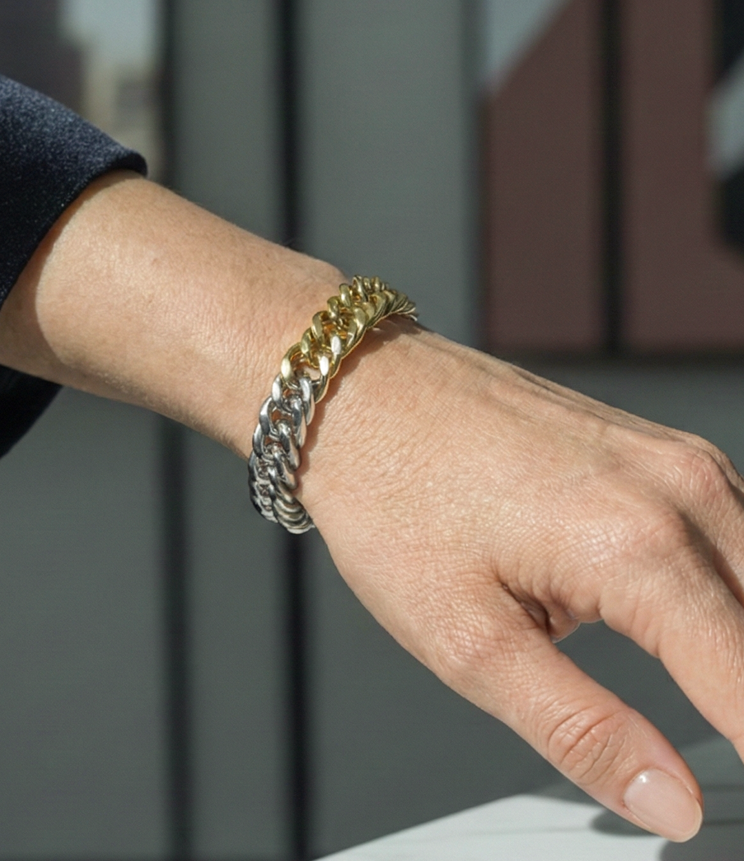 Gold chain bracelet on a wrist with a blurred background