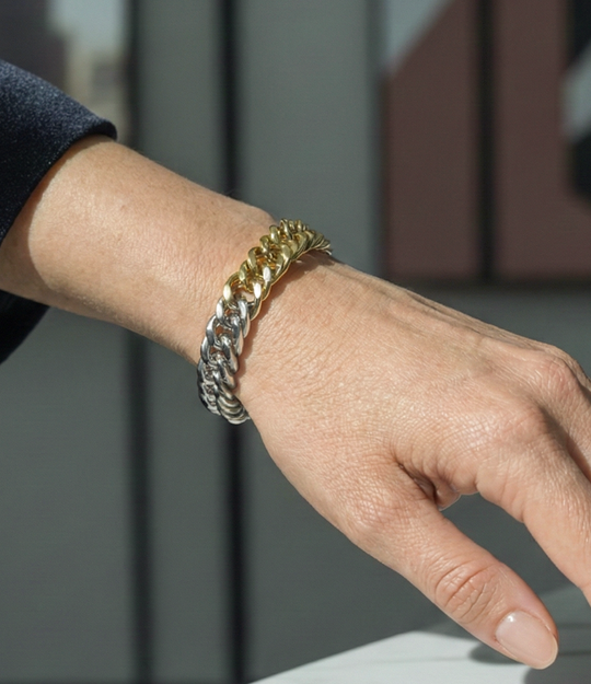 Gold chain bracelet on a wrist with a blurred background