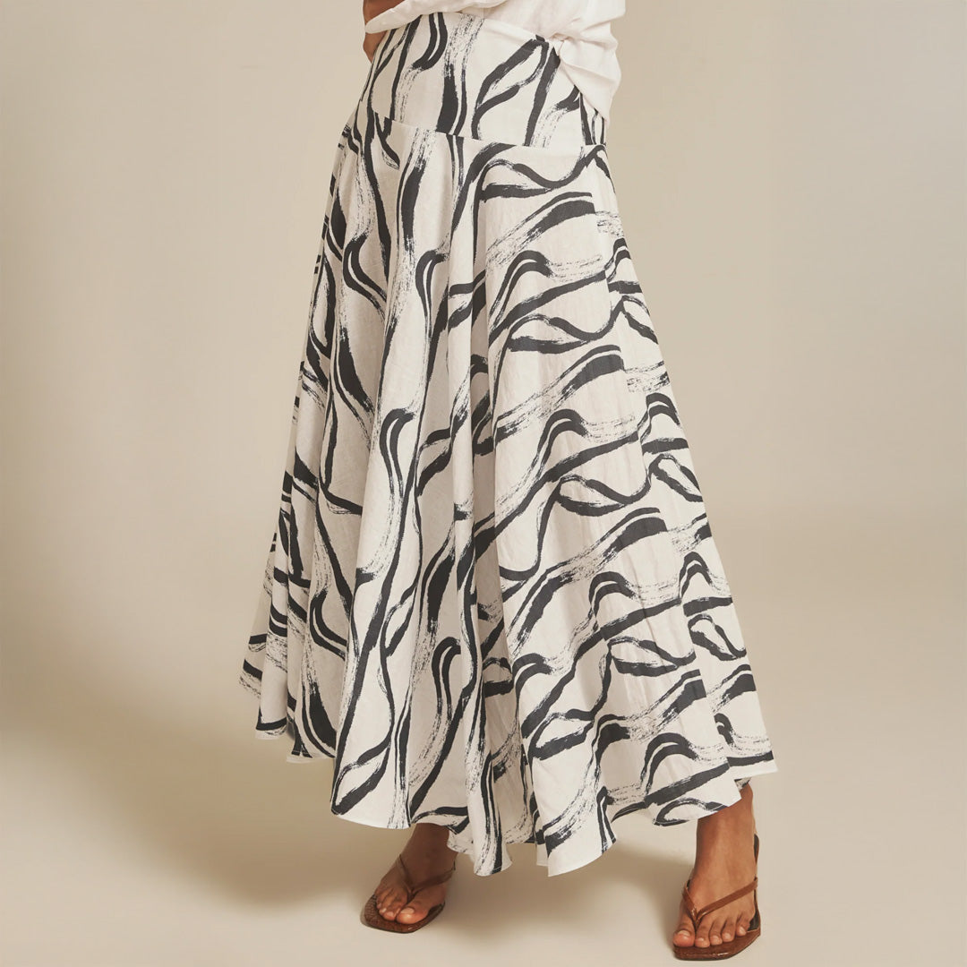 Long white skirt with black abstract pattern worn by a person on a beige background