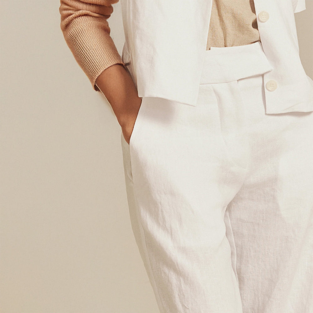 Person wearing a beige sweater and light-colored pants against a neutral background