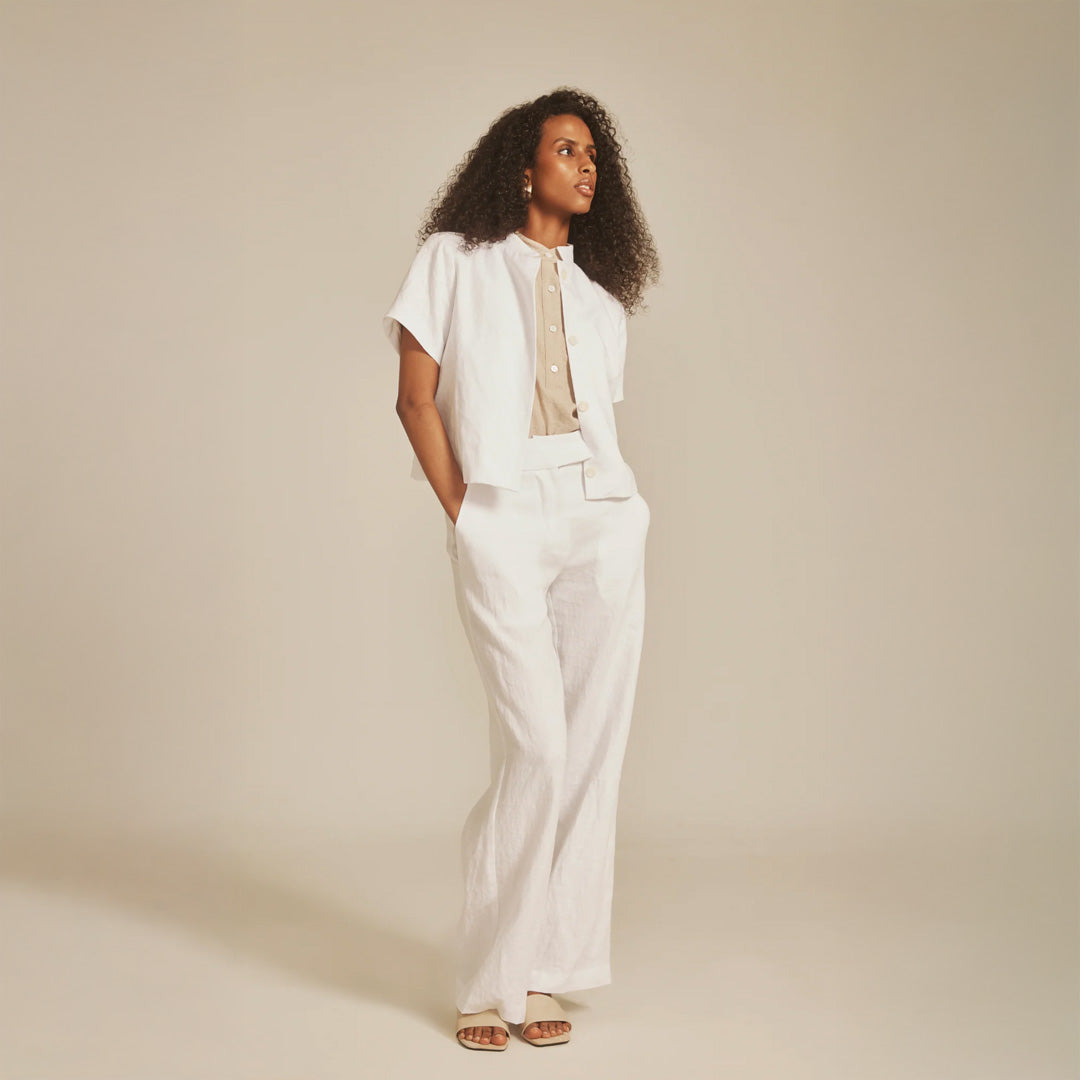 Woman wearing a white outfit against a beige background