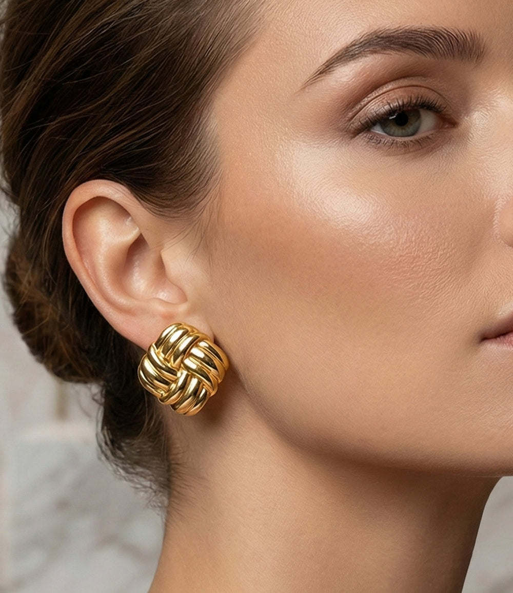 A woman wearing a gold interlaced earring